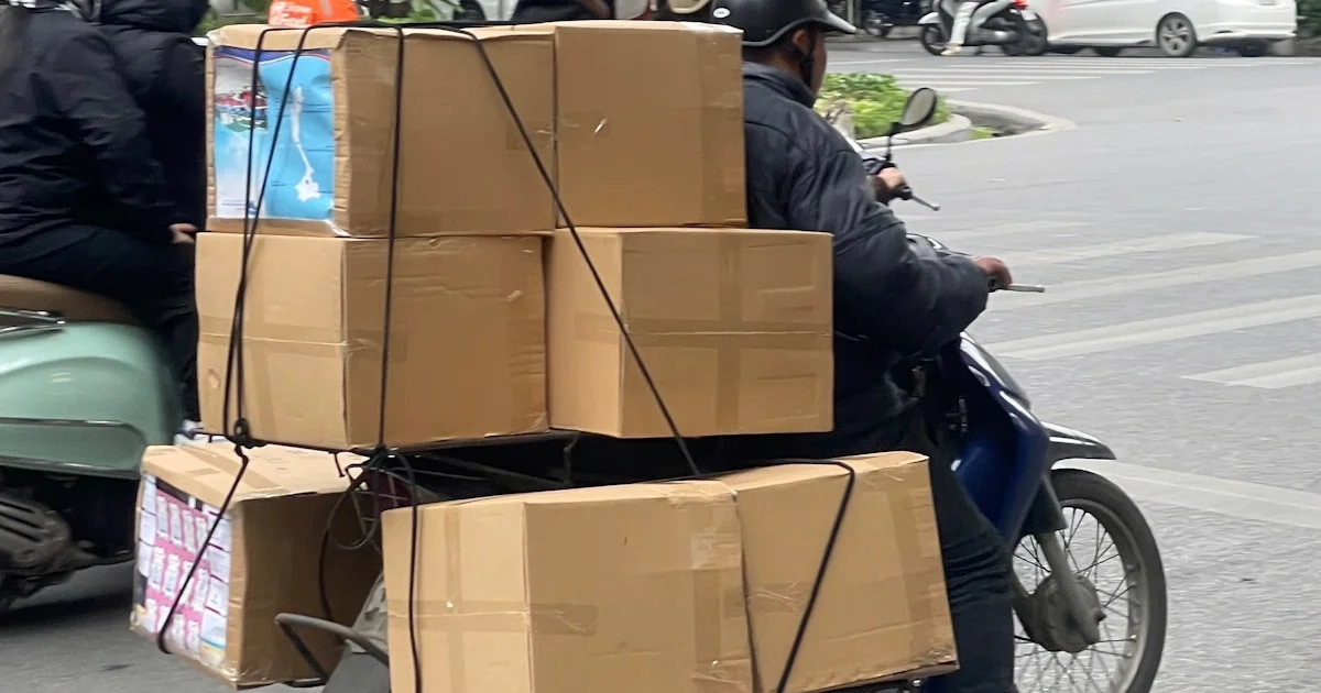 Indonesian ecommerce seller comparing courier rates with shipping boxes and marketplace dashboard visible on screen