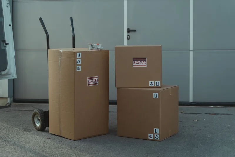 Cardboard parcels staged on a dolly outside a warehouse, ready for courier pickup