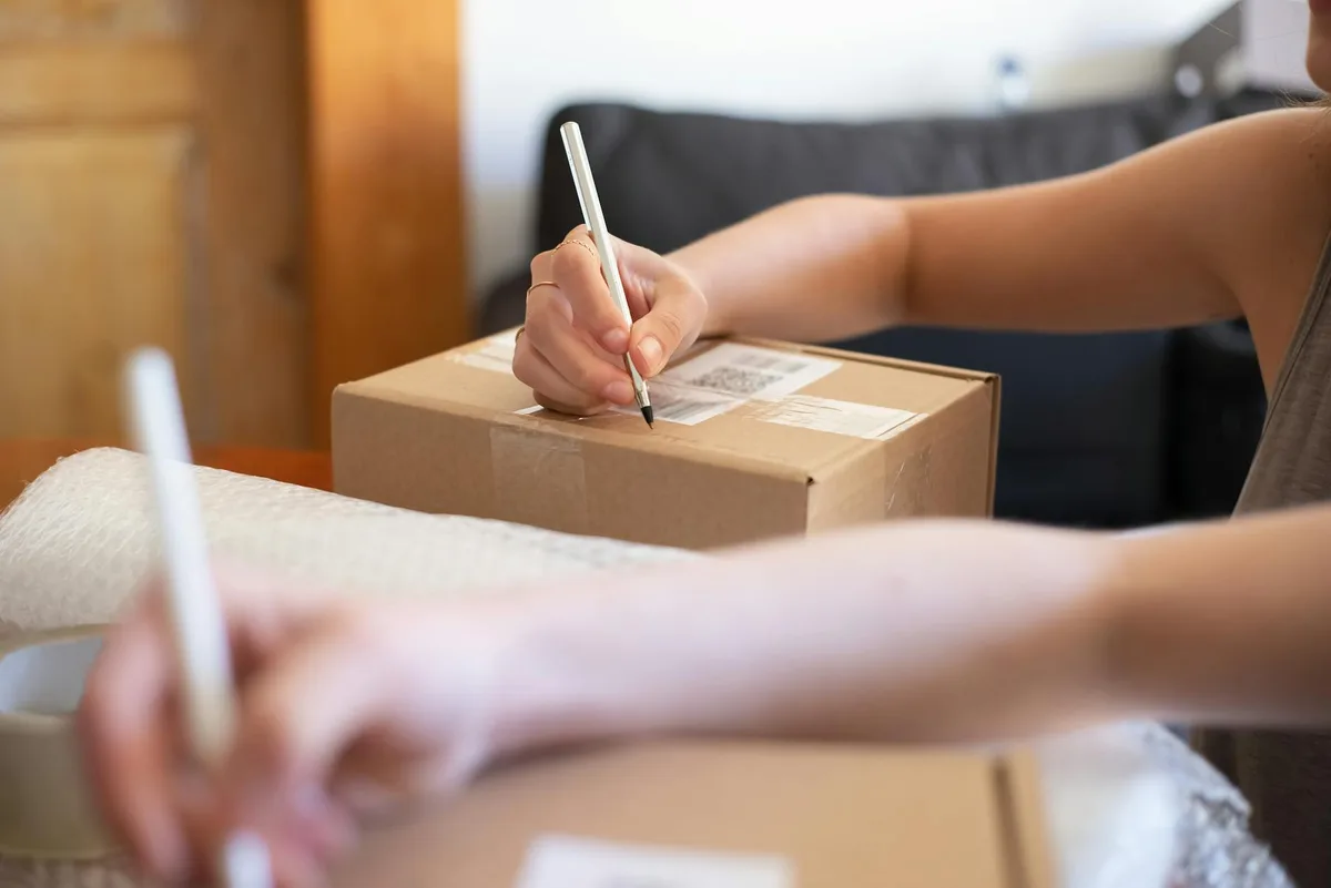 Seller examining a return parcel from Shopee with corrugated box and bubble wrap on a packing table in Malaysia