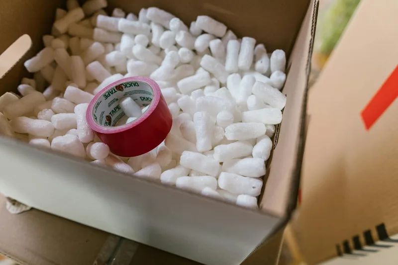 Packaging materials for Shopee returns laid out — corrugated box, bubble wrap rolls, foam sheets, and packing tape on warehouse floor in Malaysia
